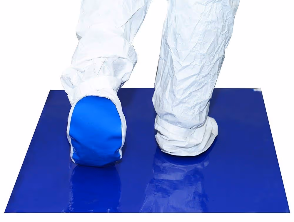 Blue sticky mat at a controlled-area entrance, used with shoe covers to capture particles